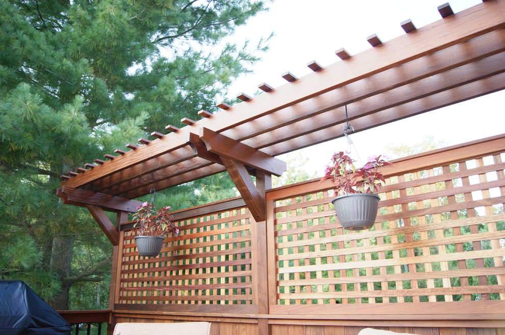 Large elegant backyard deck container garden photo in New York with a pergola