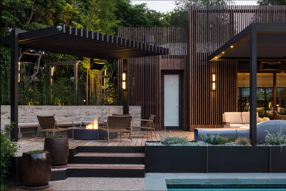 Réalisation d'une terrasse design avec un foyer extérieur et une pergola.