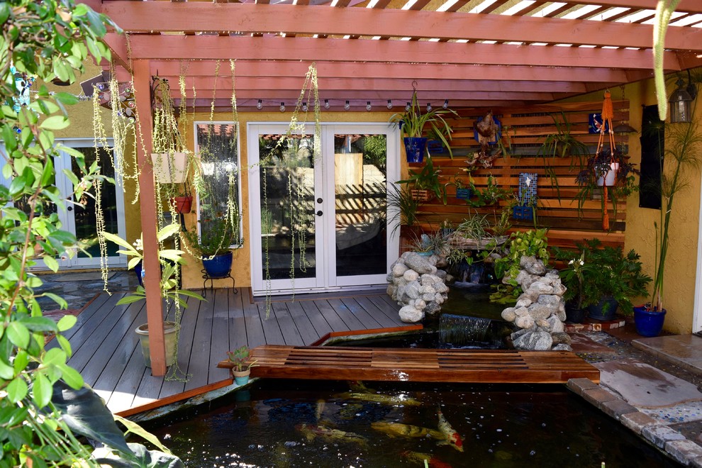 Diseño de terraza tropical de tamaño medio en patio trasero con jardín vertical y pérgola