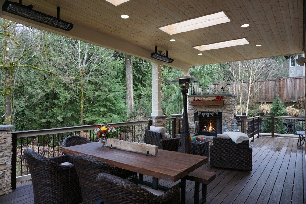 Example of a mid-sized trendy backyard deck design in Seattle with a fire pit and a roof extension
