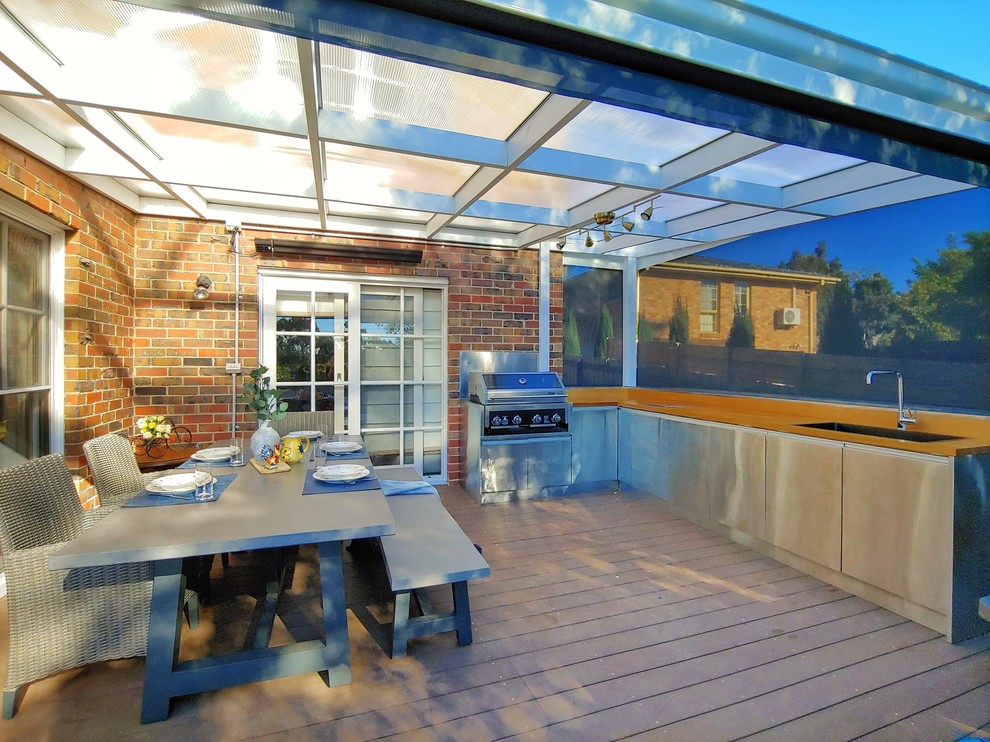 Diseño de terraza planta baja contemporánea de tamaño medio en patio trasero con cocina exterior, toldo y barandilla de madera