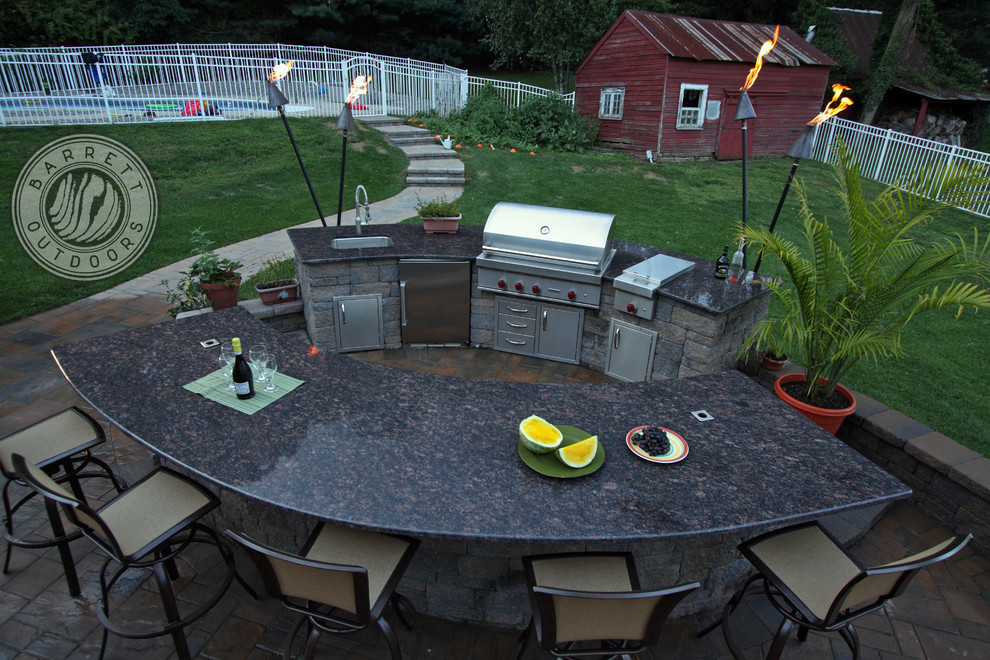 This is an example of a farmhouse back patio in New York with an outdoor kitchen.