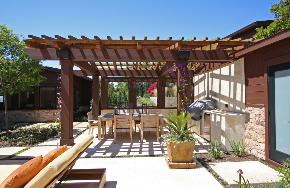 На фото: пергола на террасе среднего размера на заднем дворе в средиземноморском стиле с летней кухней с