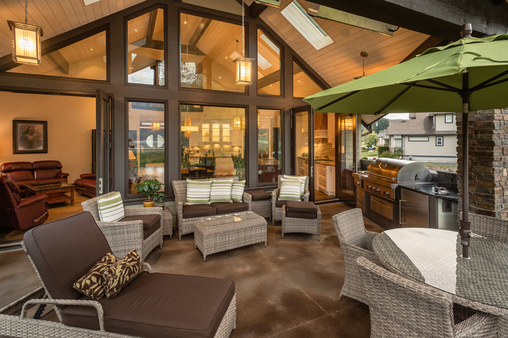 Cette image montre une grande terrasse arrière chalet avec une cuisine d'été et une extension de toiture.