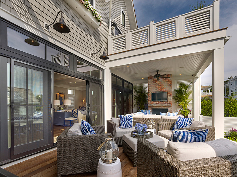 Inspiration pour une grande terrasse arrière marine avec un foyer extérieur et une extension de toiture.