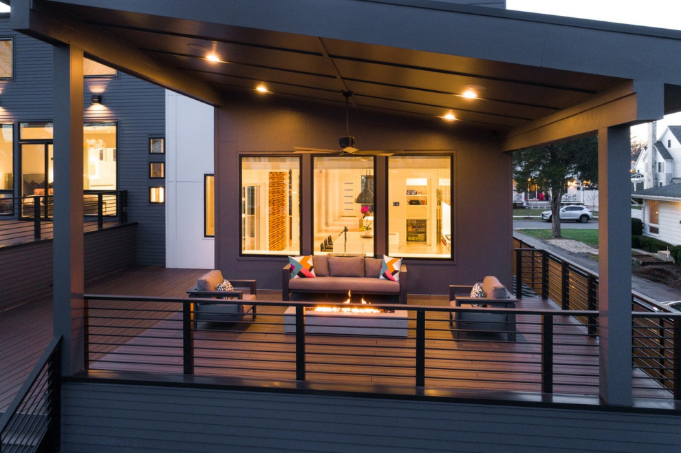 Idéer för en stor modern terrass på baksidan av huset, med en öppen spis, takförlängning och räcke i metall