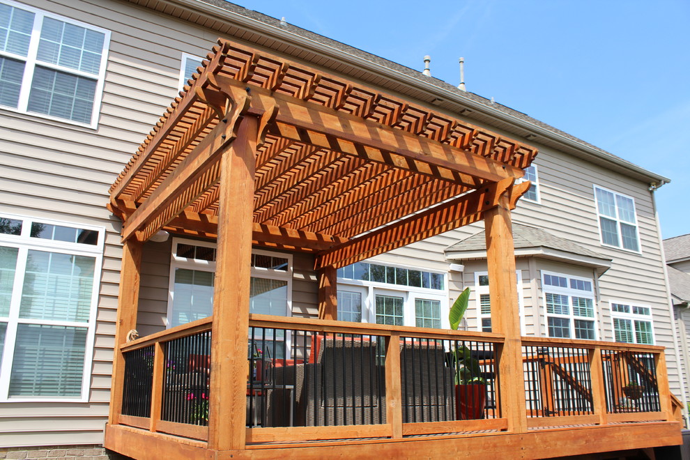 Esempio di una terrazza american style di medie dimensioni e dietro casa con un focolare e una pergola