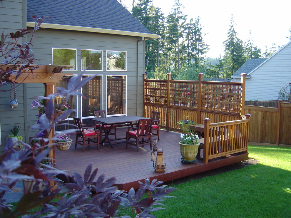 Example of a mid-sized transitional backyard deck design in Portland with a pergola