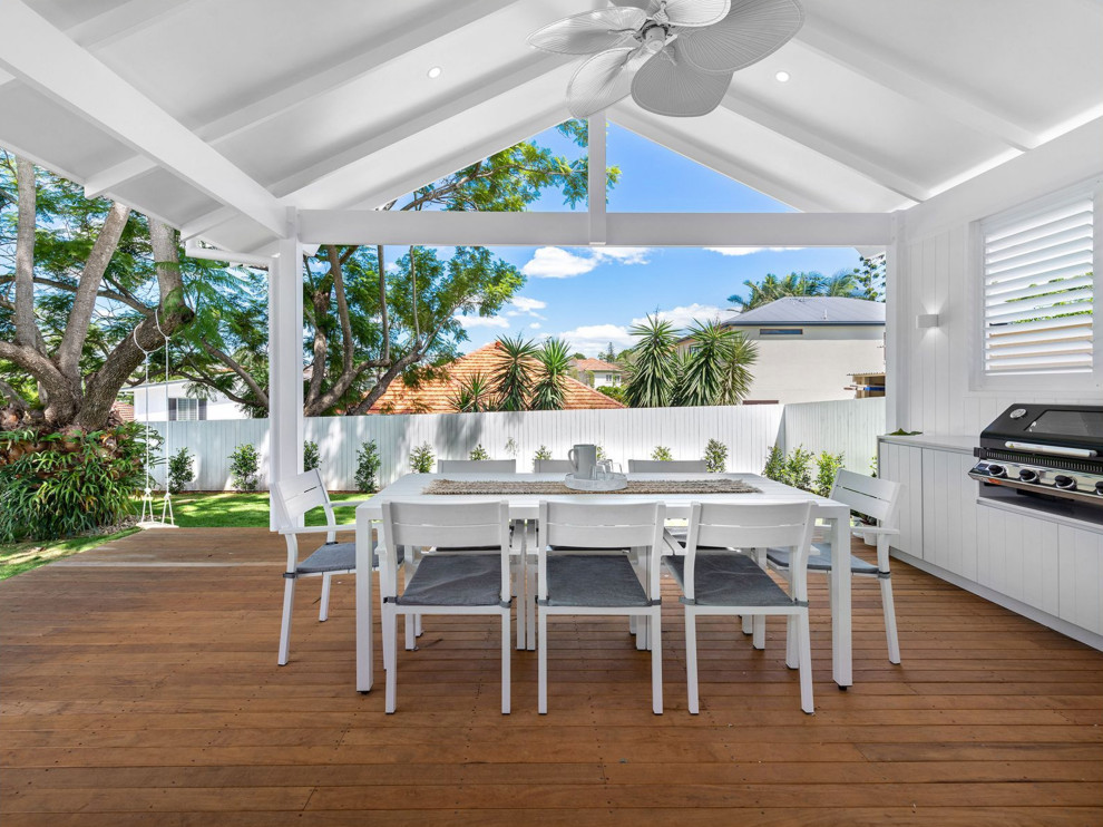Example of a large minimalist backyard deck design in Brisbane with a roof extension