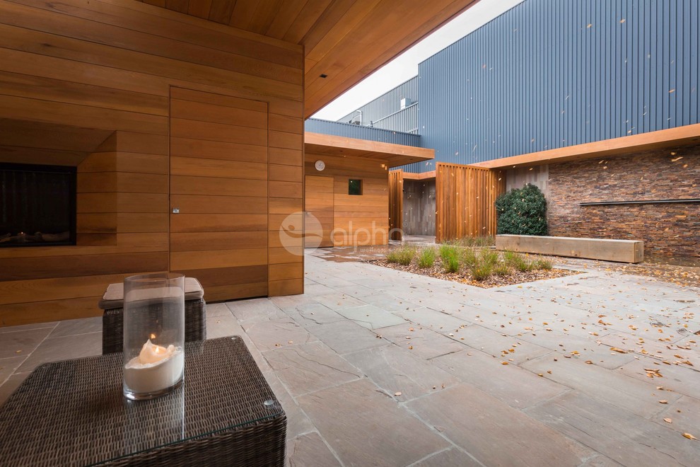This is an example of an expansive modern back terrace in Dallas with an outdoor shower and a roof extension.