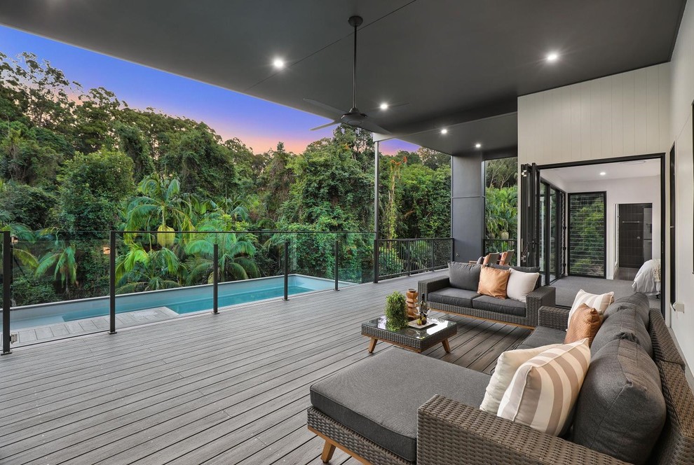 Example of a trendy backyard deck design in Sunshine Coast with a roof extension