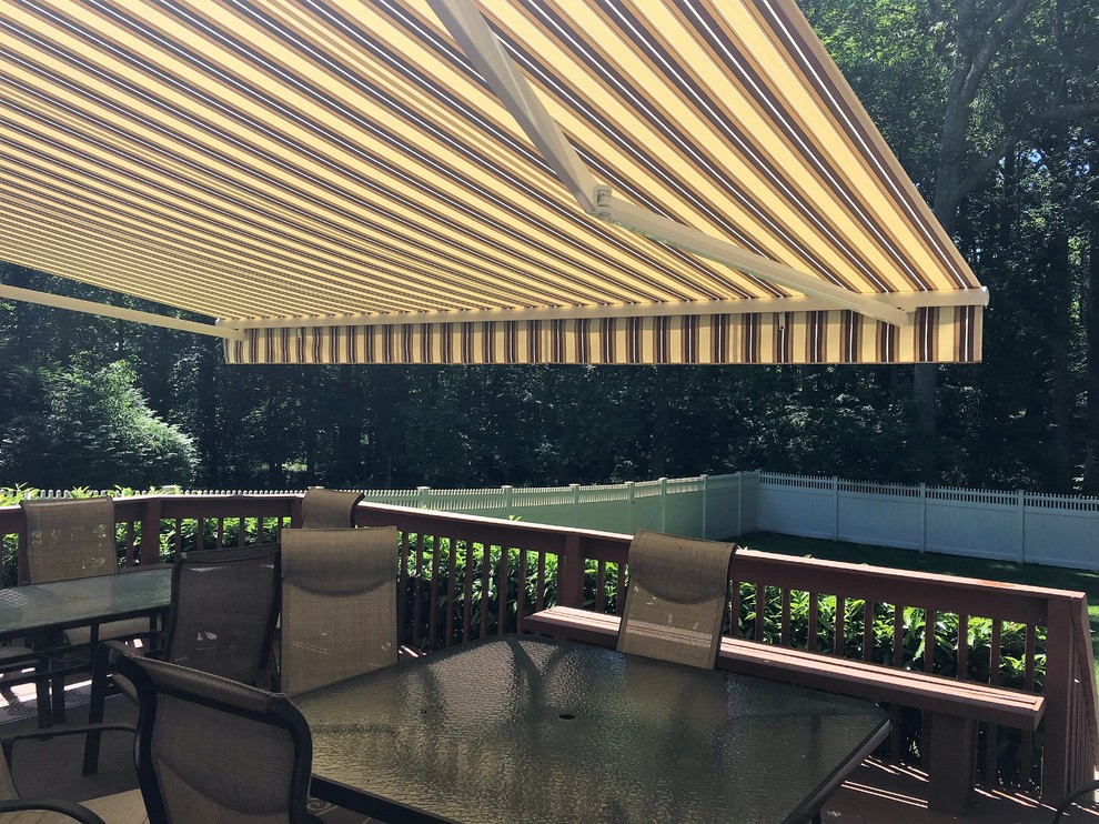 This is an example of a large coastal back terrace in New York with an awning.