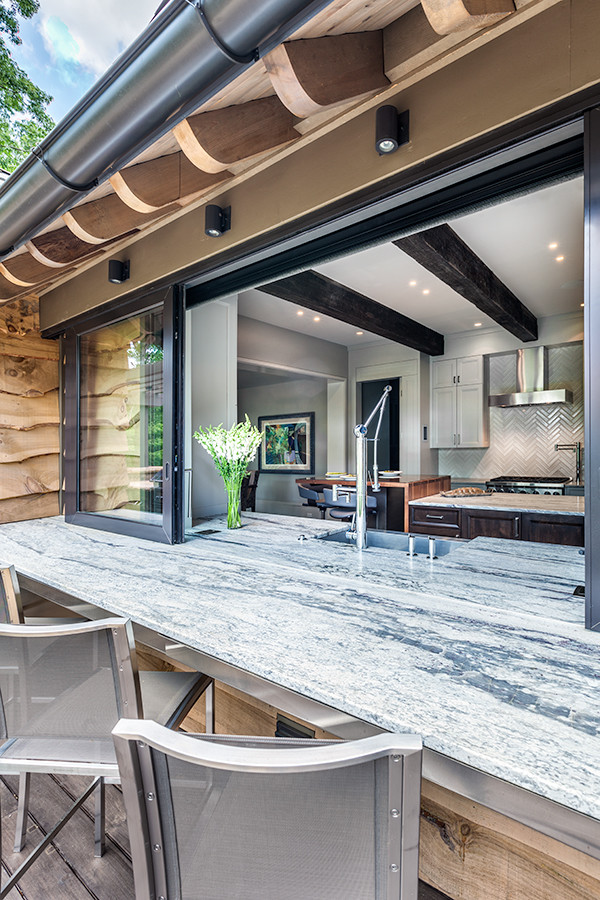 Große, Überdachte Moderne Terrasse hinter dem Haus mit Outdoor-Küche in Sonstige