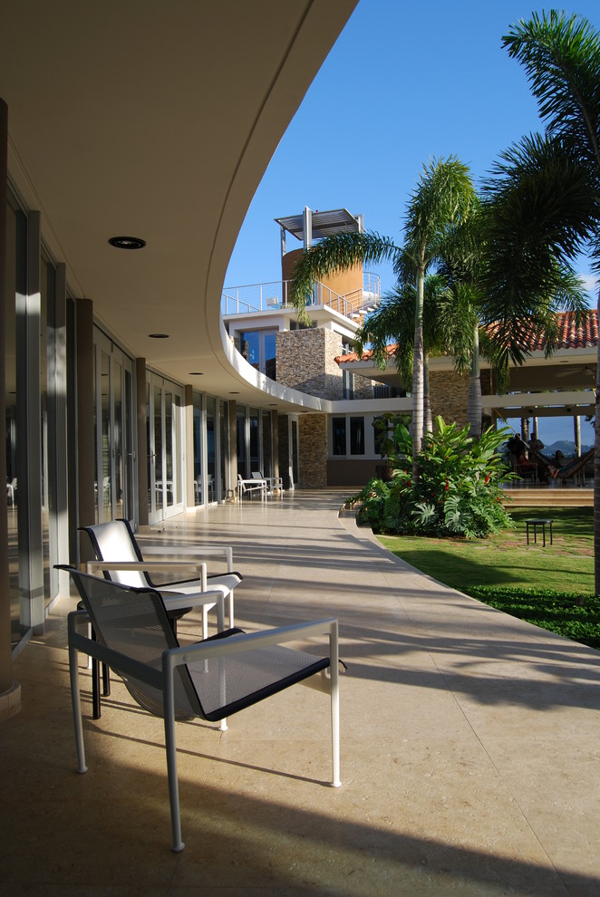 Foto på en stor tropisk terrass på baksidan av huset, med takförlängning