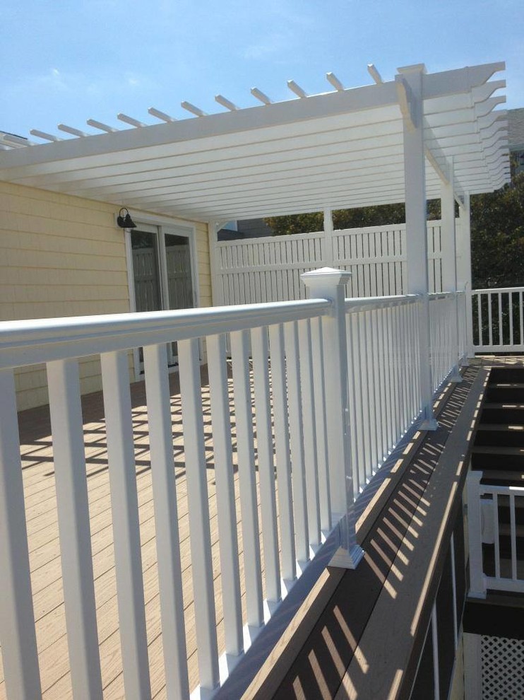 Example of a small beach style rooftop deck design in Other with a pergola