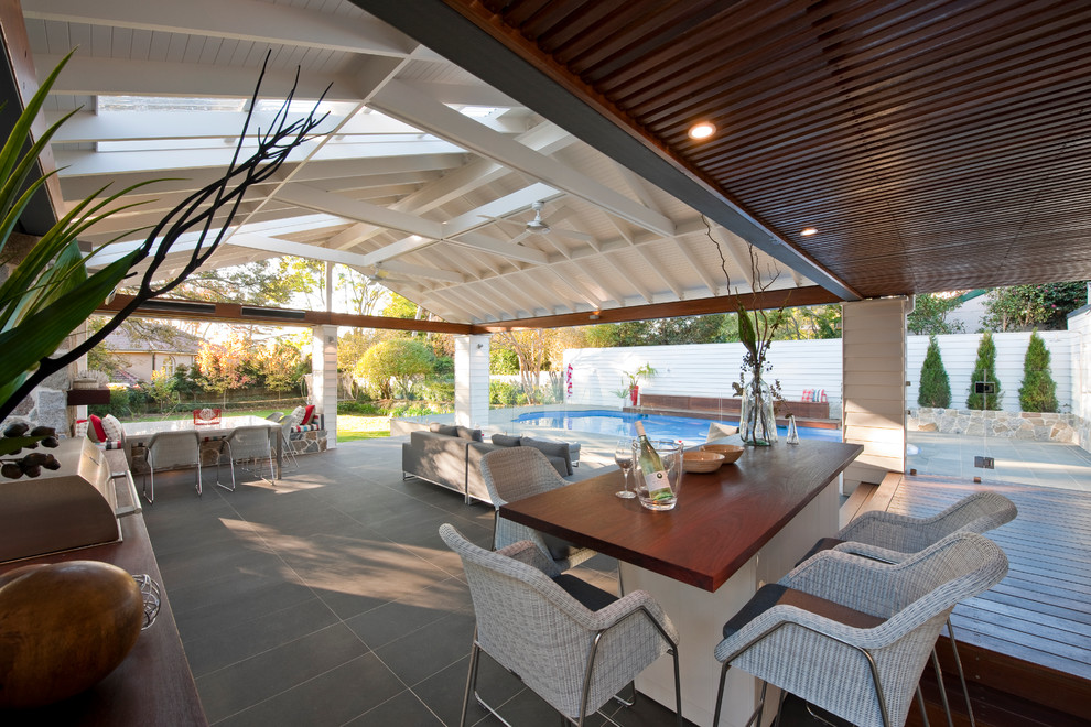 Large back terrace in Sydney with an outdoor kitchen and a roof extension.