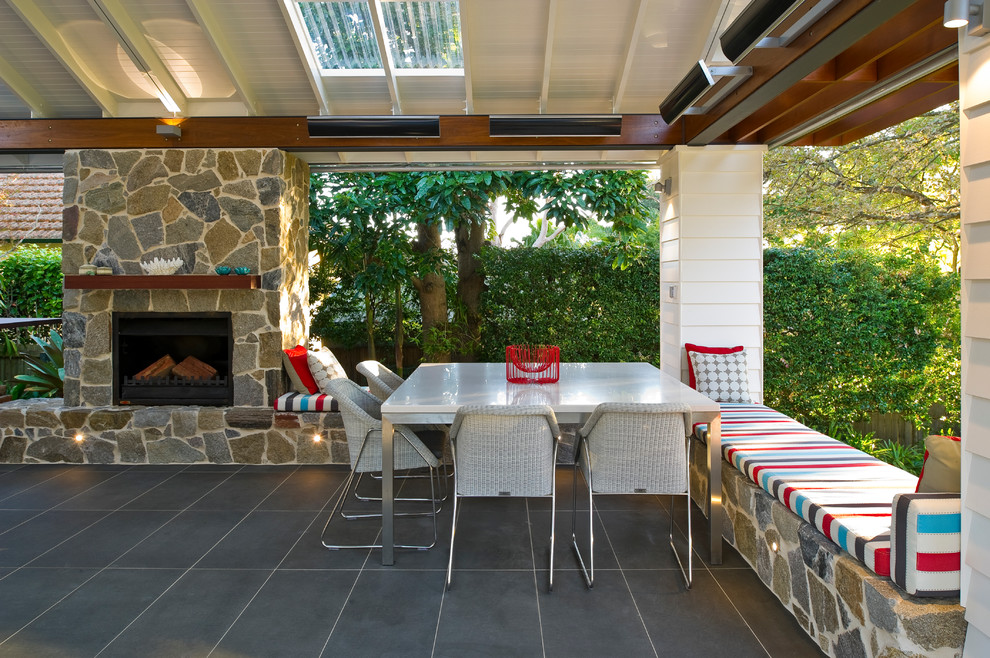 Example of a large backyard deck design in Sydney with a fire pit and a roof extension