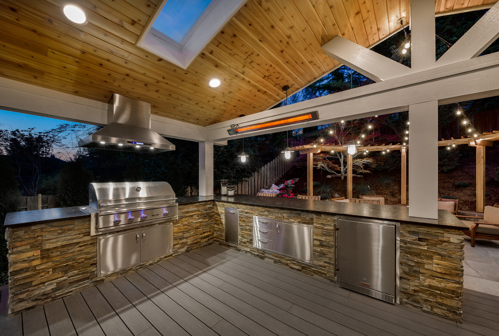 Réalisation d'une grande terrasse arrière tradition avec une cuisine d'été et une extension de toiture.
