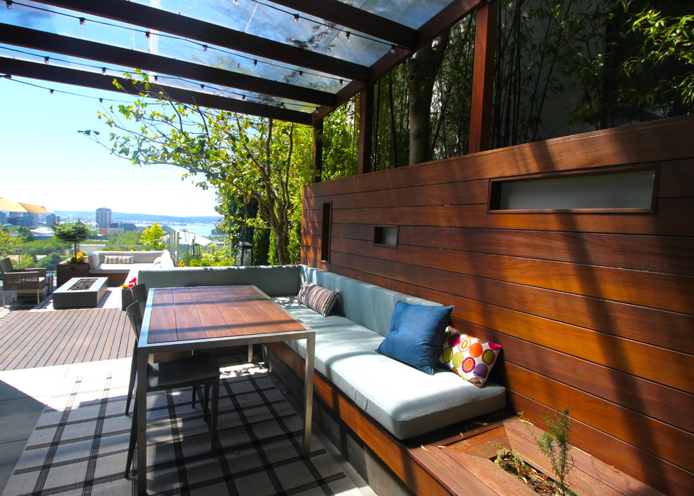 Cette photo montre une terrasse tendance avec une extension de toiture et un foyer extérieur.