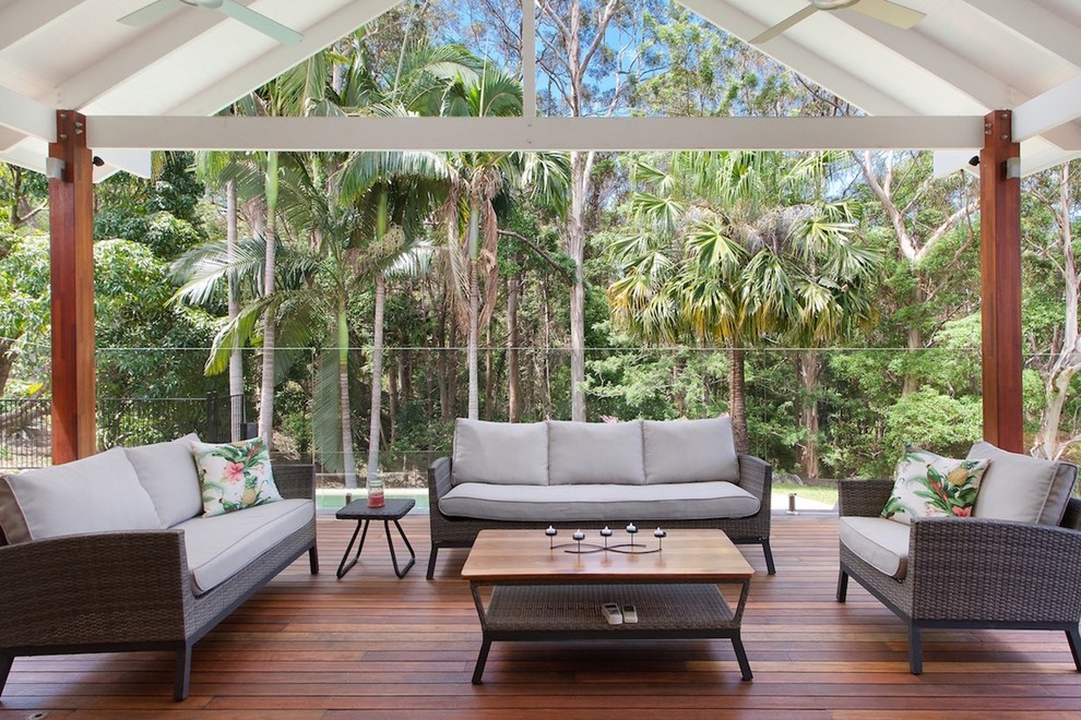 Example of a transitional backyard deck design in Sunshine Coast with a roof extension