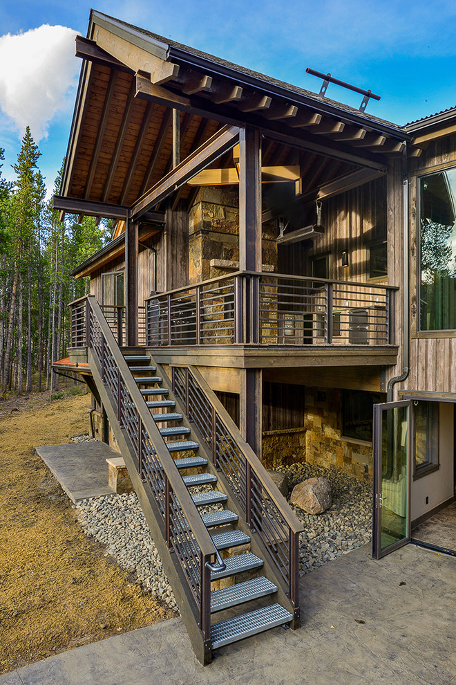 Cette image montre une grande terrasse arrière chalet avec une cuisine d'été et une extension de toiture.