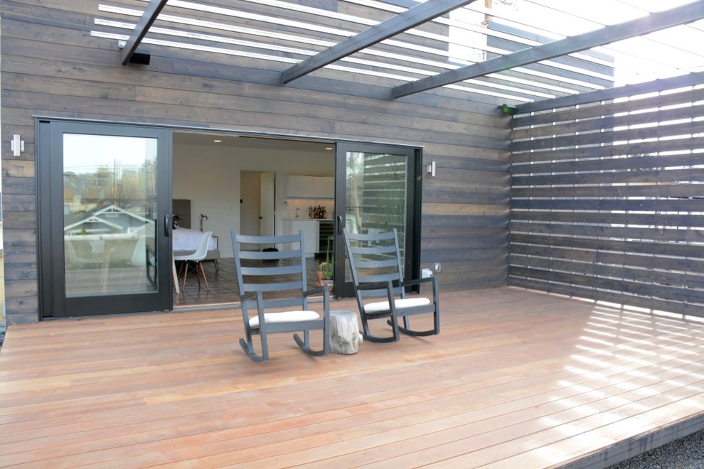 Ejemplo de terraza minimalista de tamaño medio en patio trasero con pérgola