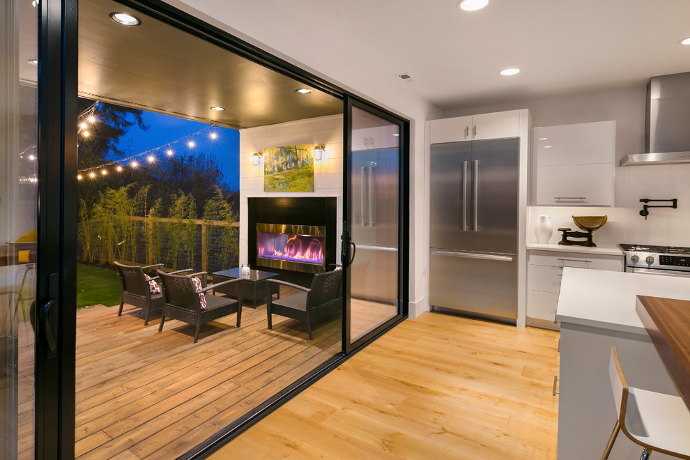 Example of a trendy backyard deck design in Seattle with a fireplace and a roof extension