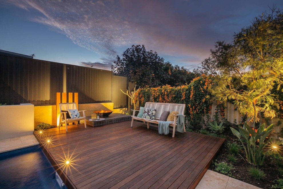 На фото: терраса на заднем дворе в стиле модернизм с местом для костра без защиты от солнца