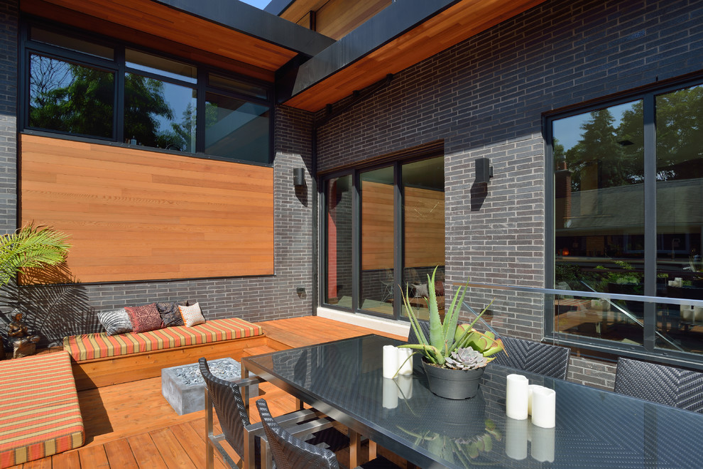 Example of a large trendy backyard deck design in Toronto with a fire pit