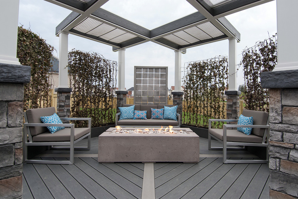 Example of a mid-sized urban backyard deck design in Toronto with a fire pit and a pergola
