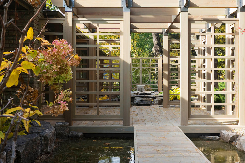 Diseño de terraza de estilo zen de tamaño medio en patio trasero con fuente y pérgola