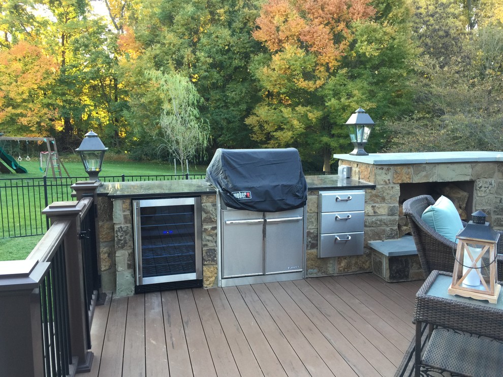 Example of a large classic backyard deck design in Philadelphia with a fireplace and a roof extension