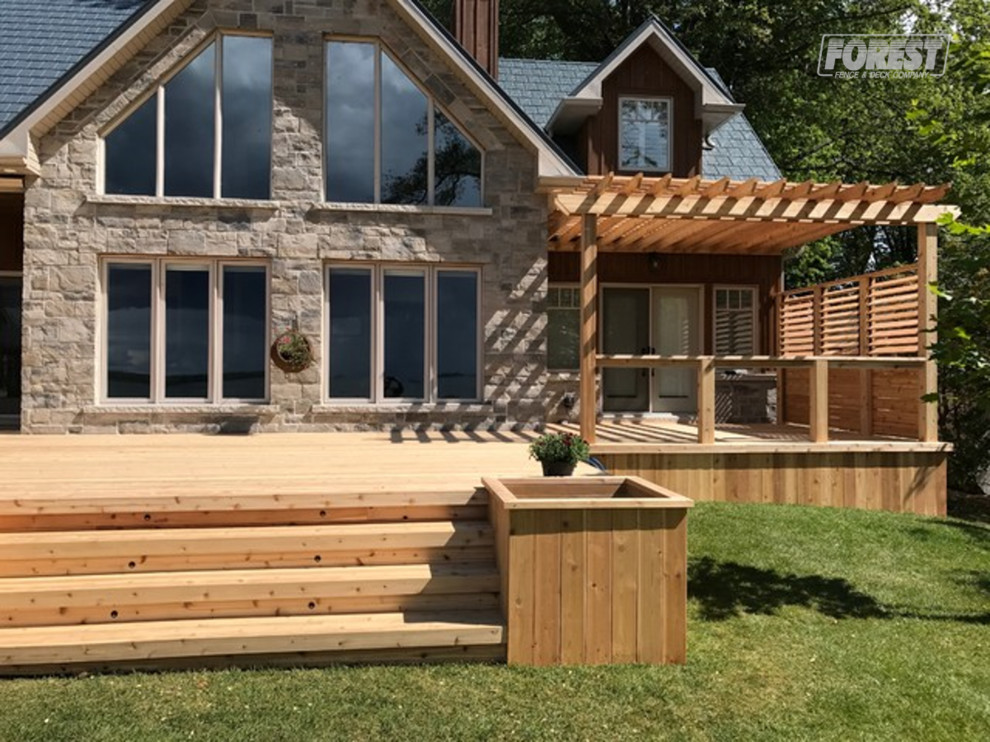 Large backyard deck photo in Toronto with a pergola