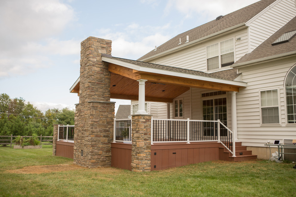 Idée de décoration pour une terrasse arrière tradition de taille moyenne avec un foyer extérieur et une extension de toiture.