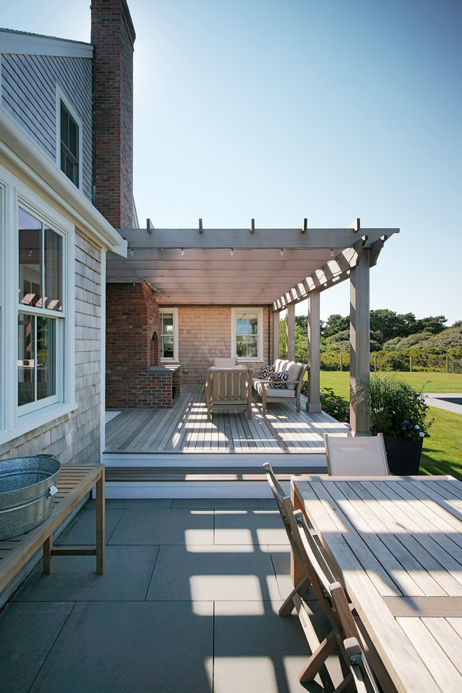 Idee per una terrazza stile marinaro dietro casa con un focolare e una pergola