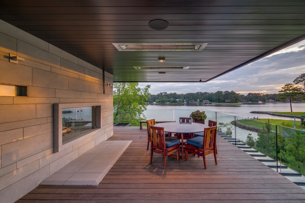 Inspiration pour une grande terrasse arrière minimaliste avec un foyer extérieur et une extension de toiture.