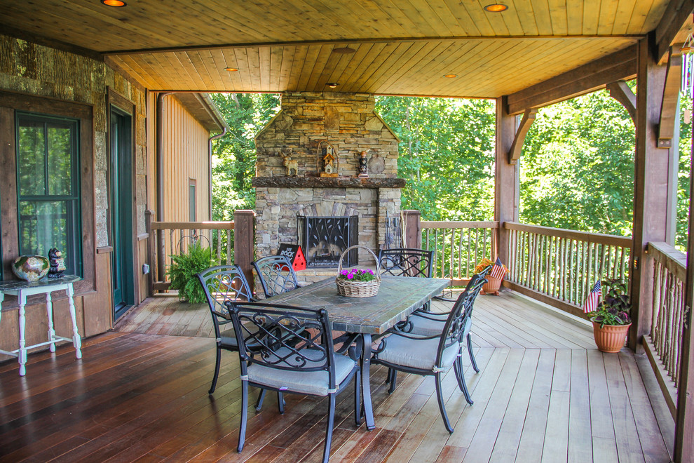 This is an example of a large rustic back terrace in Charlotte with a fire feature and a roof extension.