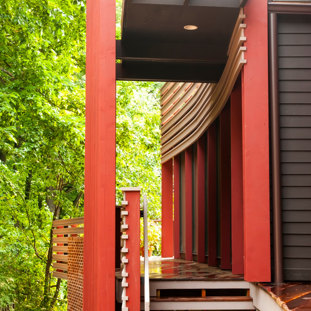 Aménagement d'une façade de maison rouge moderne en bois et bardage à clin de taille moyenne et à un étage avec un toit à quatre pans, un toit en métal et un toit noir.