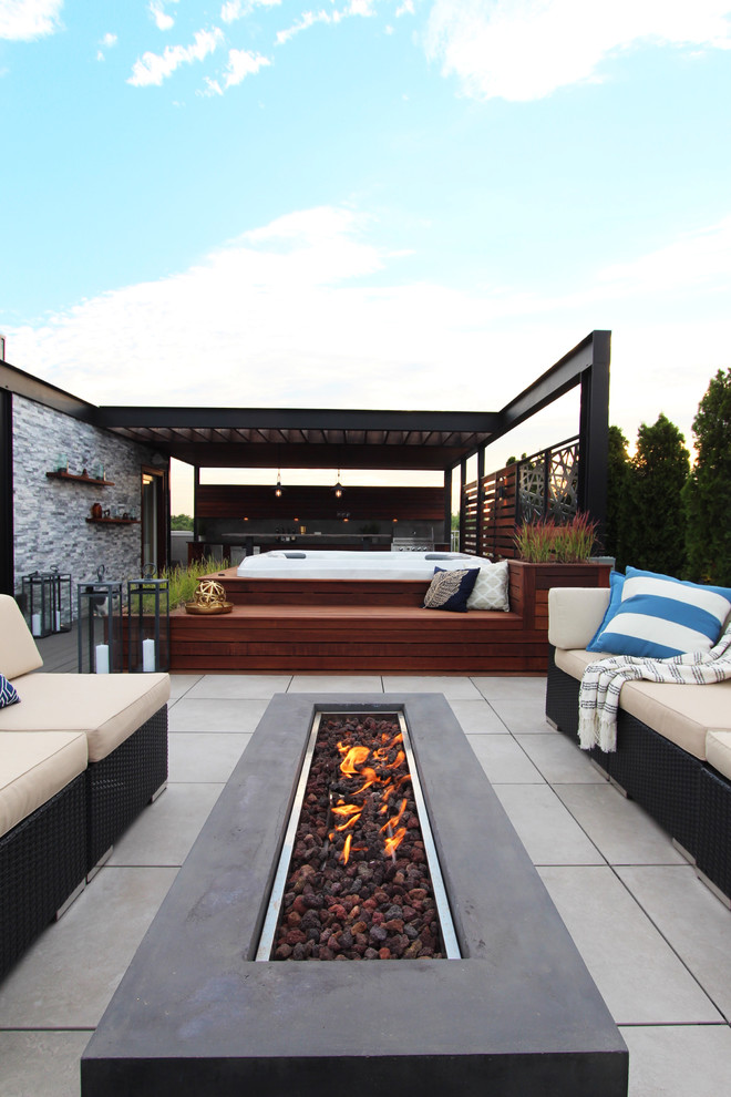 Cette image montre une terrasse design avec un foyer extérieur et une pergola.