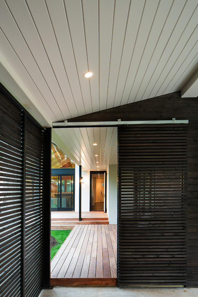 Example of a mid-sized transitional backyard deck design in Austin with a roof extension