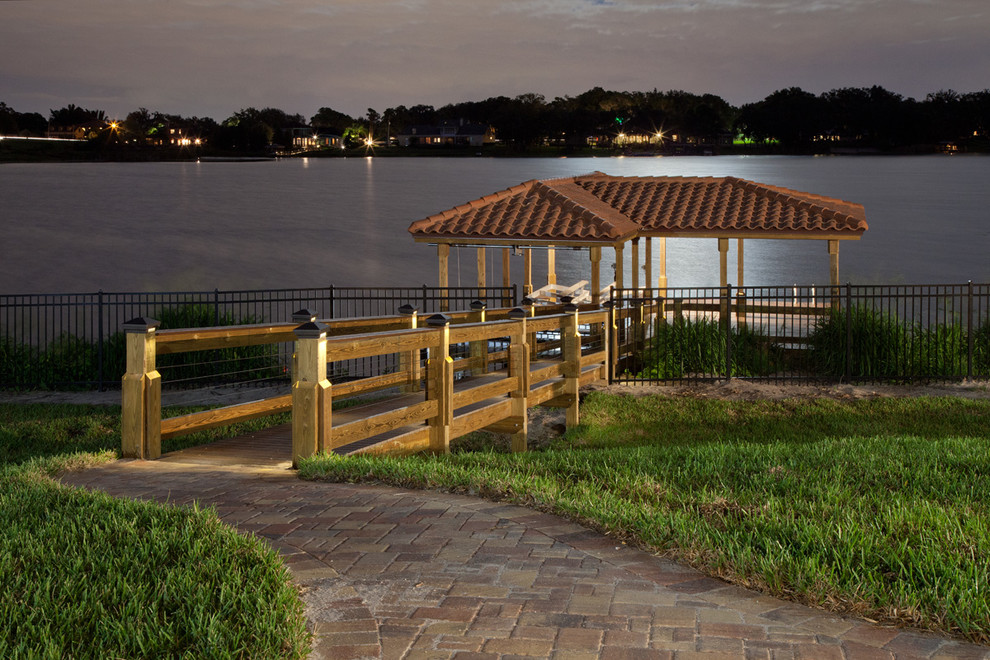 Dock - large mediterranean backyard dock idea in Orlando with a roof extension