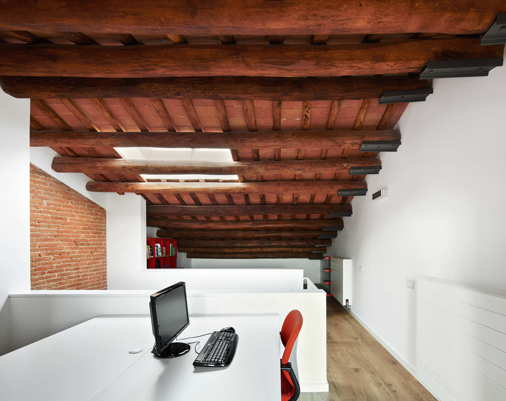 Modelo de despacho industrial grande sin chimenea con paredes blancas, suelo de madera en tonos medios y escritorio independiente