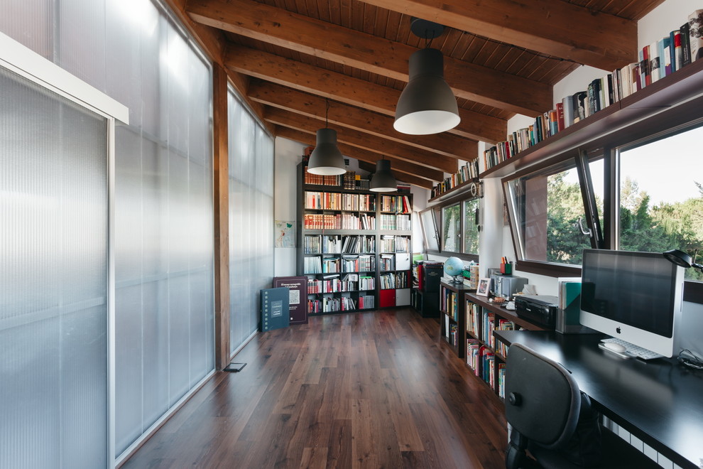 Großes Modernes Arbeitszimmer ohne Kamin mit Arbeitsplatz, weißer Wandfarbe, dunklem Holzboden und freistehendem Schreibtisch in Barcelona