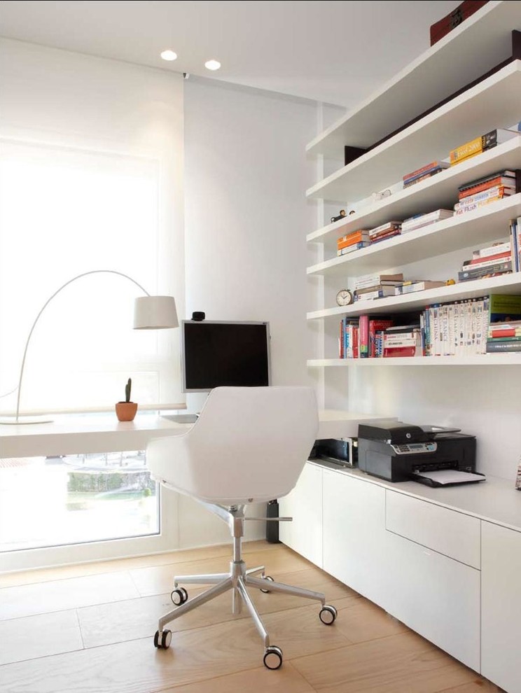 Modelo de despacho actual de tamaño medio sin chimenea con paredes blancas, suelo de madera clara y escritorio empotrado
