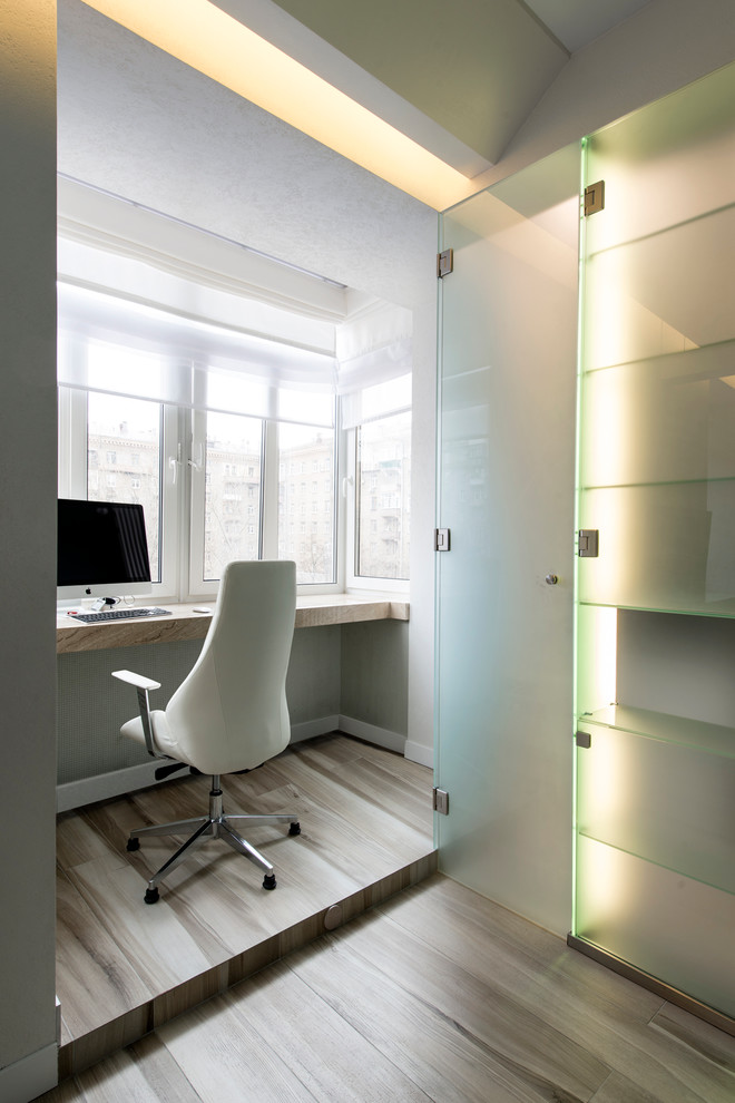 Foto de despacho contemporáneo con paredes grises, suelo de madera clara y escritorio empotrado