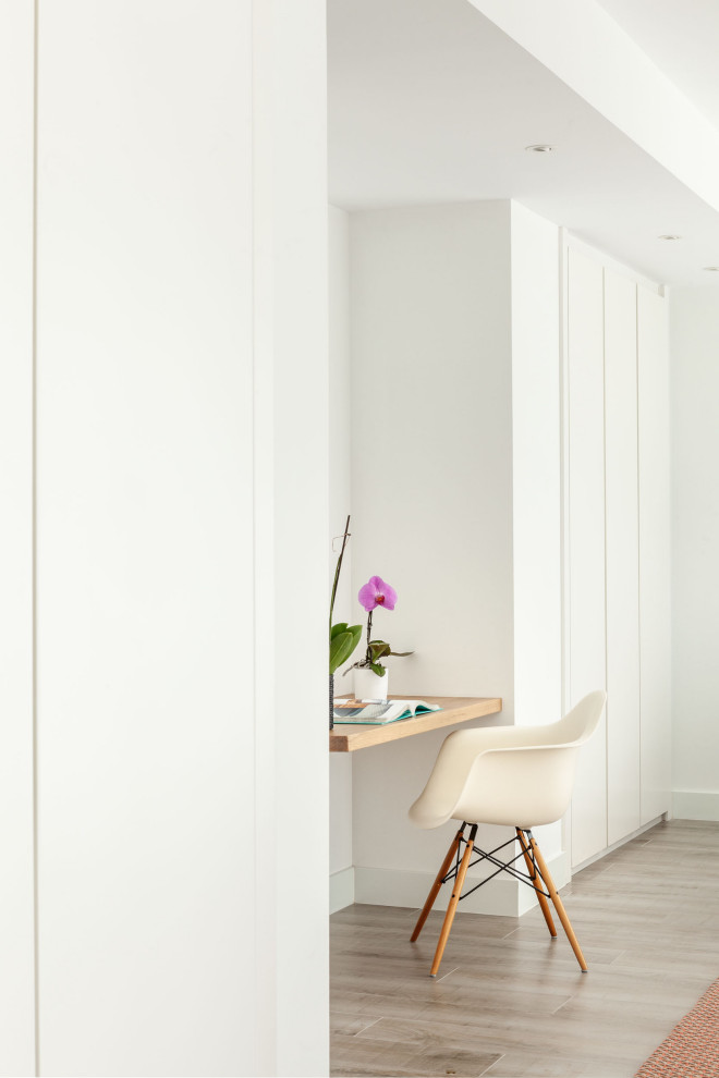 Modernes Arbeitszimmer mit Arbeitsplatz, weißer Wandfarbe, hellem Holzboden, freistehendem Schreibtisch und weißem Boden in Madrid