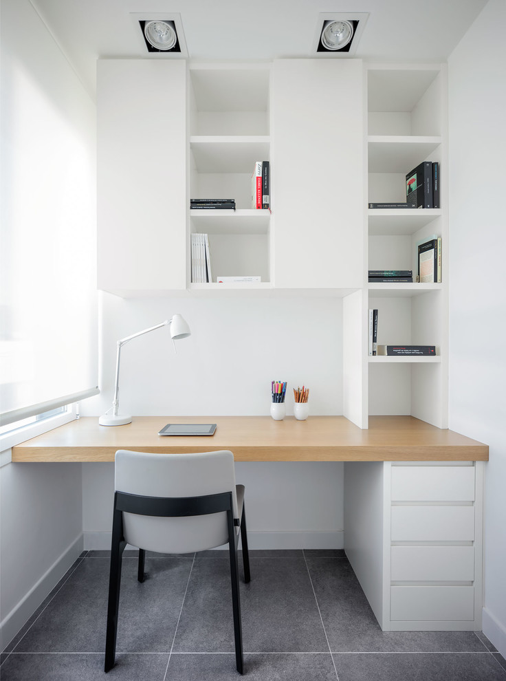 Стильный дизайн: маленький кабинет в скандинавском стиле с белыми стенами, встроенным рабочим столом и серым полом для на участке и в саду - последний тренд