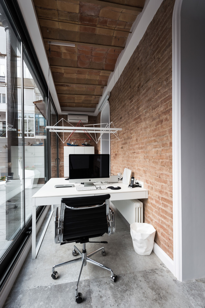 Kleines Industrial Arbeitszimmer ohne Kamin mit Betonboden, Einbau-Schreibtisch, Arbeitsplatz und oranger Wandfarbe in Barcelona