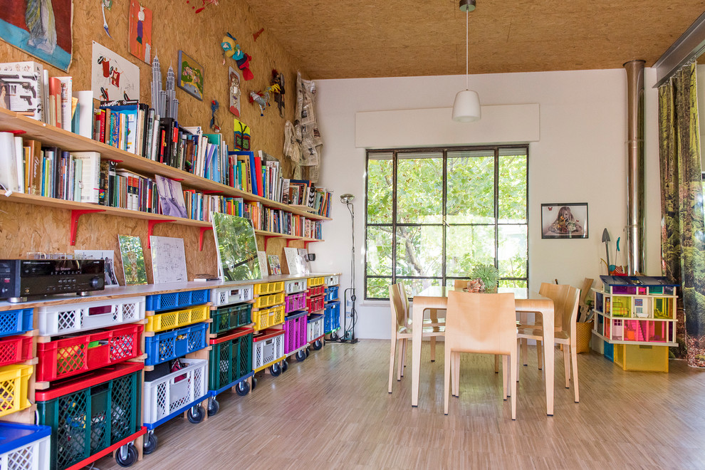 Inredning av ett eklektiskt stort hemmabibliotek, med vita väggar, ljust trägolv och ett fristående skrivbord