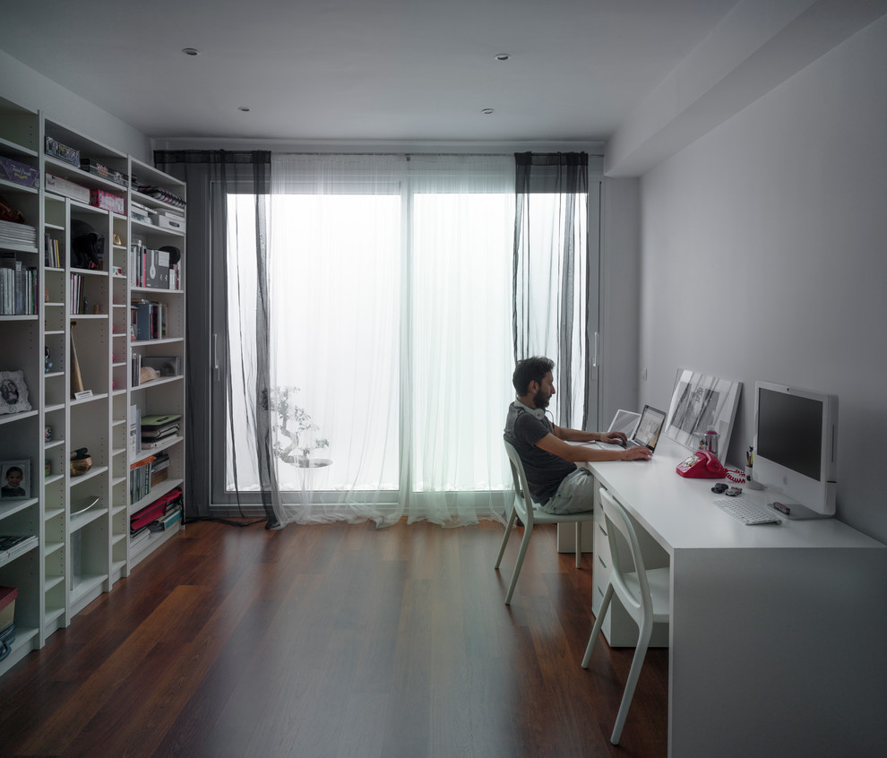Kleines Modernes Arbeitszimmer mit Studio, weißer Wandfarbe, dunklem Holzboden und freistehendem Schreibtisch in Sevilla